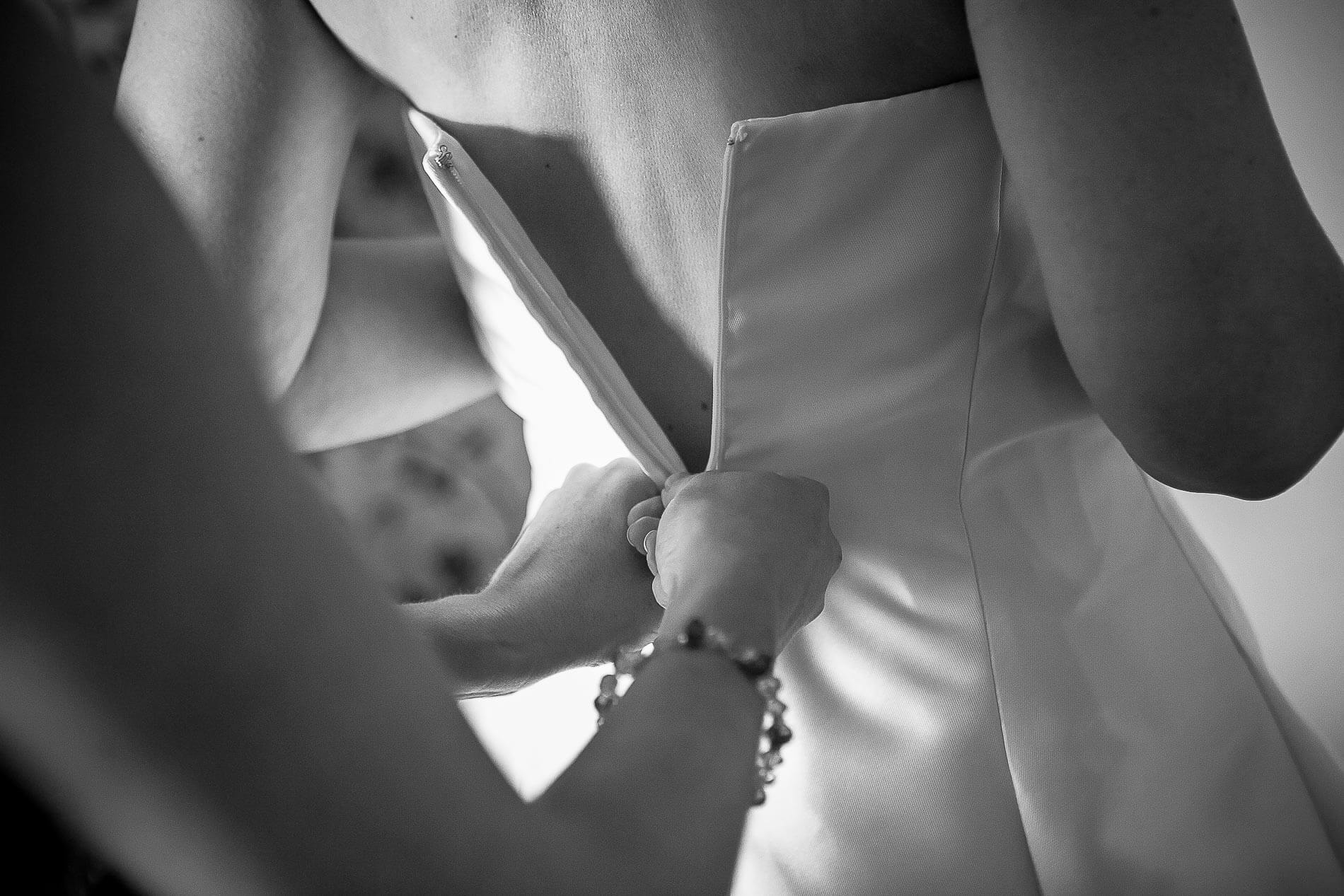 bride having the zip pulled up on her wedding dress